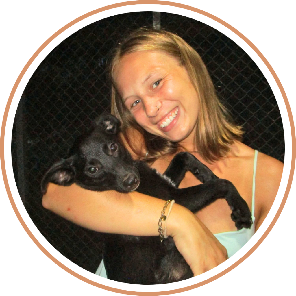 Voluntario Stina con cachorro negro en brazos.